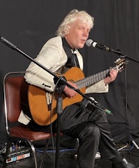 a man playing an acoustic guitar in front of a microphone